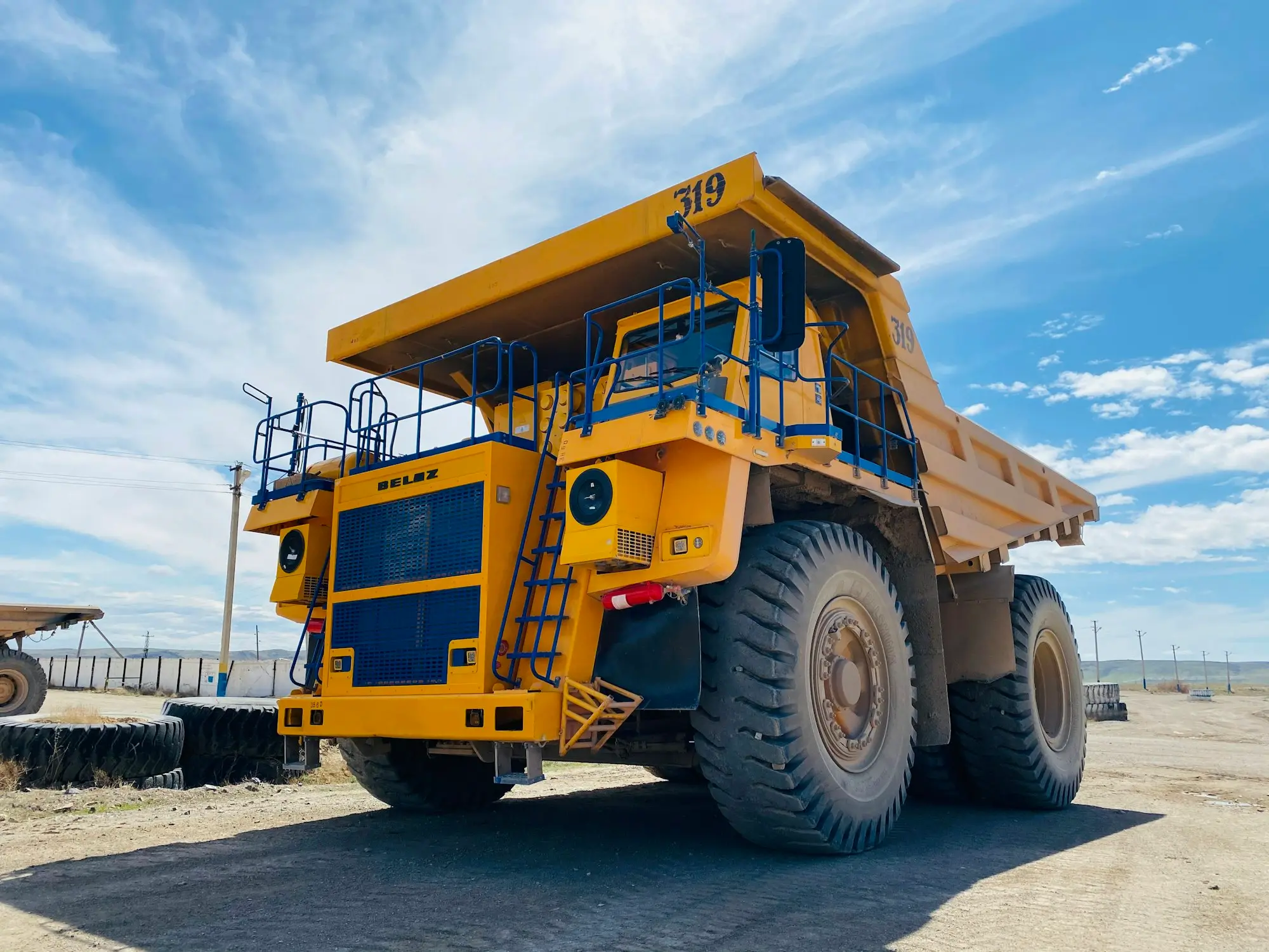 Large yellow heavy-equipment dump truck parked on a dirt yard under a blue sky, the kind of asset a lender values as security